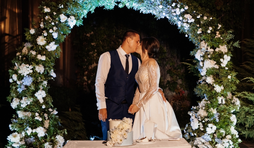 A bride and groom share a kiss beneath a floral arch at The Cinderella House wedding chapel in Myrtle Beach, SC.