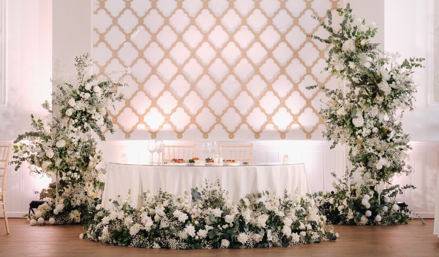 A wedding reception table adorned with elegant white flowers and lush greenery at The Venue in Myrtle Beach, SC.