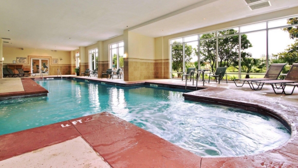 Indoor heated pool at Marina Inn, featuring a spacious area with lounge chairs and bright lighting.