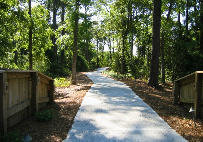 A serene wooded walkway with trees and benches, promoting calmness at the Autism Friendly Hotel in Myrtle Beach.