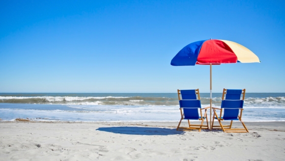 A pair of beach chairs and a large umbrella on the sand, ideal for families at a kid-friendly resort in Myrtle Beach.