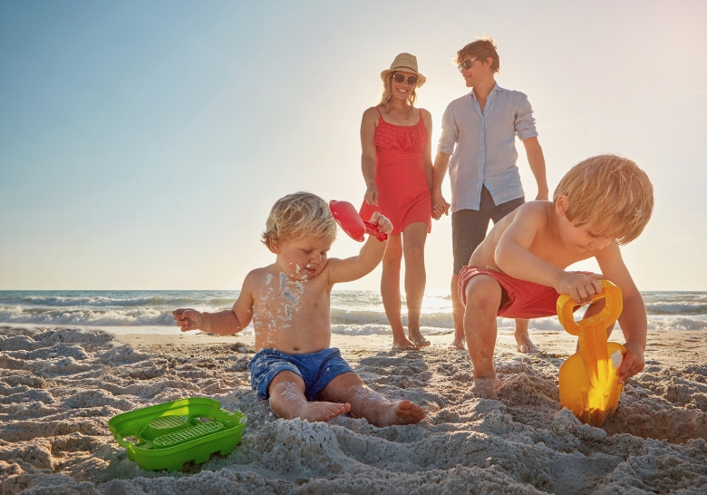 A family enjoys playing with sand toys on the beach at a kid-friendly resort in Myrtle Beach.