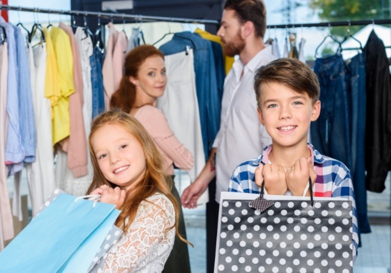 A family happily holds shopping bags in a clothing store, highlighting a joyful shopping experience together.