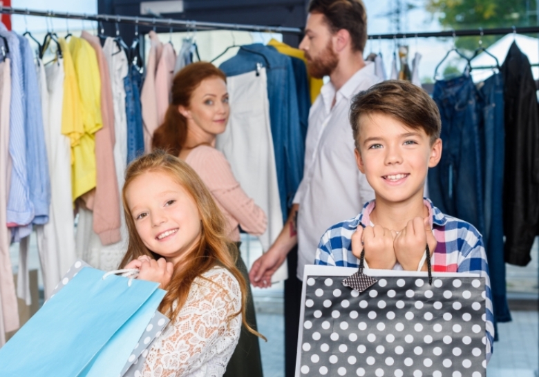 A family happily holds shopping bags in a clothing store, highlighting a joyful shopping experience together.
