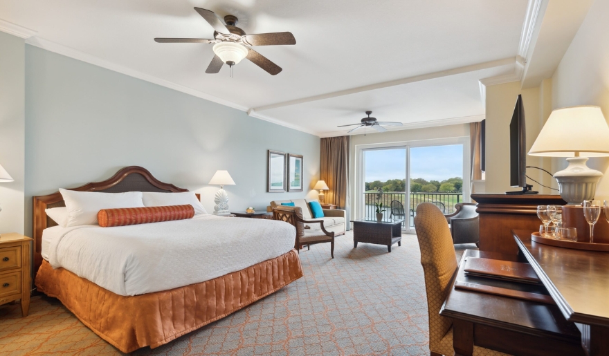 A comfortable hotel room showcasing a king bed, television, and balcony, suitable for autism-friendly experiences in Myrtle Beach.