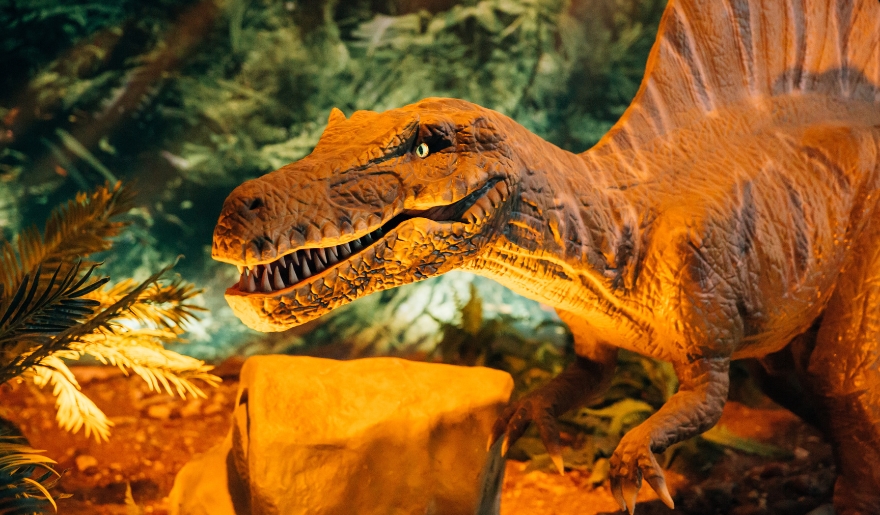 A dinosaur is depicted in front of a tree at Dinoland Cafe, highlighting a playful experience for families in Myrtle Beach.
