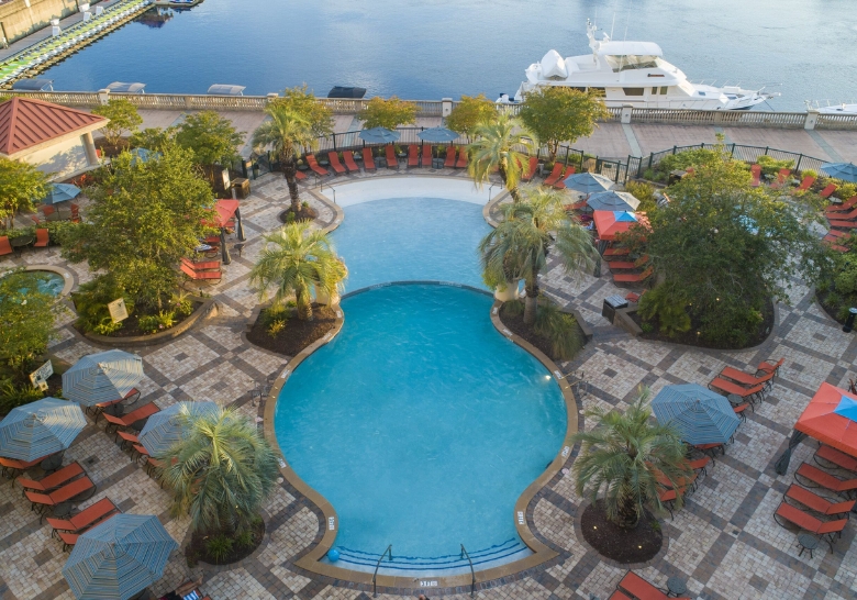 A family-friendly pool area with lounge chairs and umbrellas beside a tranquil body of water at Myrtle Beach condos.