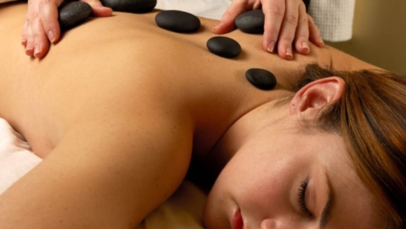 A woman enjoys a relaxing hot stone massage at a luxury spa in Myrtle Beach, highlighting family-friendly services.