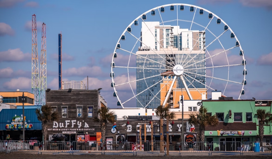 The Myrtle Beach SkyWheel building is visible behind a vibrant Ferris wheel, perfect for Myrtle Beach Attractions for Kids