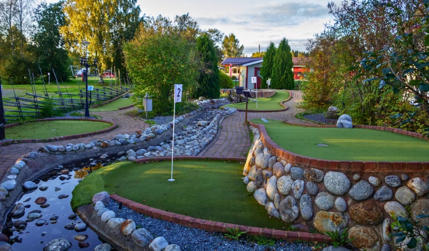 A vibrant miniature golf course with a flowing stream and rocks, perfect for kids' entertainment at Myrtle Beach Attractions.