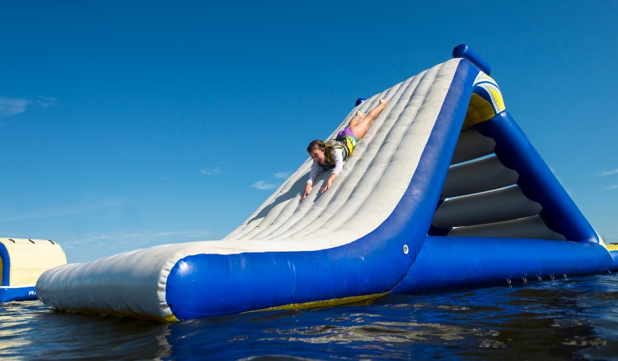 An individual sliding down a vibrant inflatable water slide at Shark Wake Park, a family-friendly destination in Myrtle Beach.