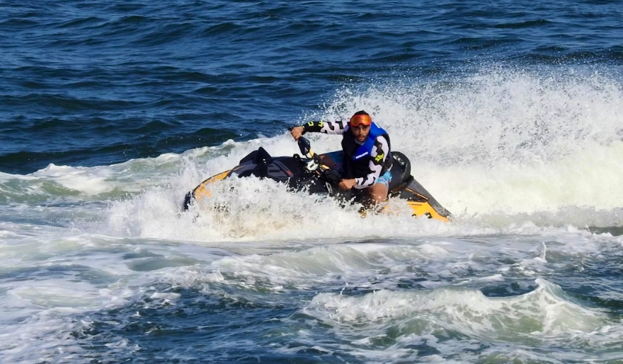 A man riding a jet ski across the ocean waves at Myrtle Beach, showcasing boat rentals and water sports activities.