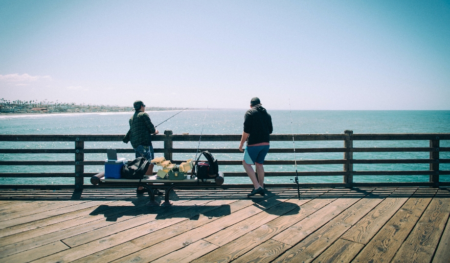 Two individuals on a pier with fishing rods, engaged in a fishing charter activity at Myrtle Beach.