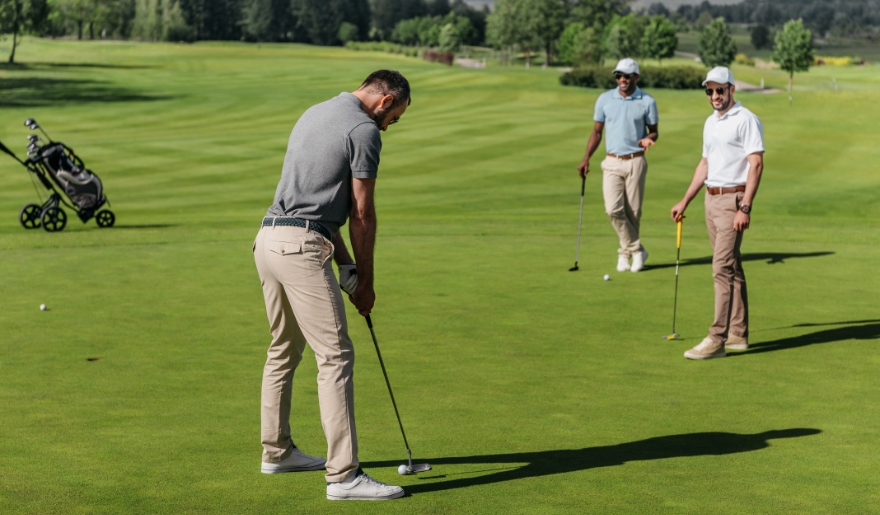 A group of three men playing golf on a vibrant green field during a Myrtle Beach outing.