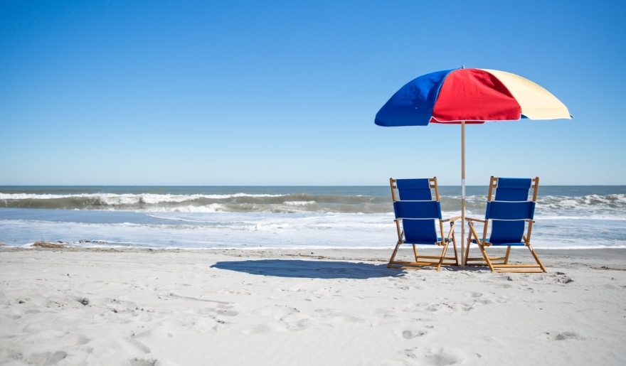 Two beach chairs and a large umbrella set up on the sand, ideal for a private beach day at Myrtle Beach.