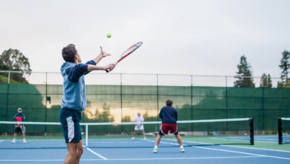 Tennis courts in Grande Dunes, Myrtle Beach Hotel, with players engaged in a match under clear skies.