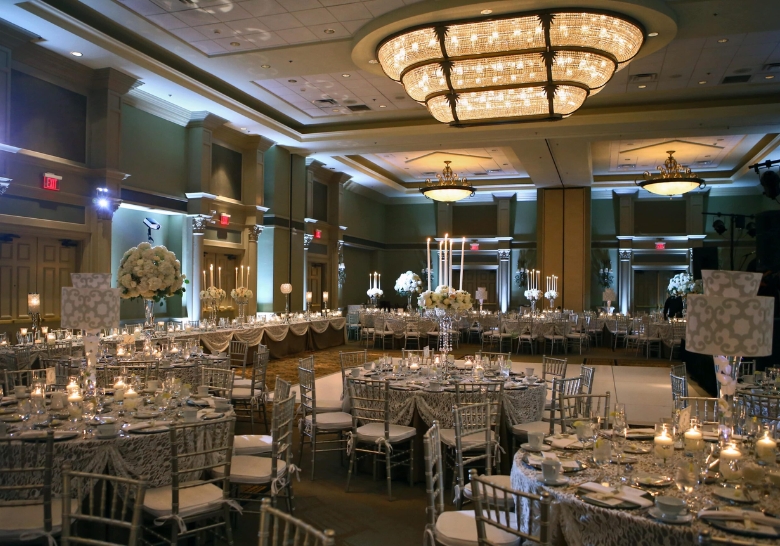 A spacious banquet room featuring elegant white and silver tables, designed for large group events at Myrtle Beach Hotel.