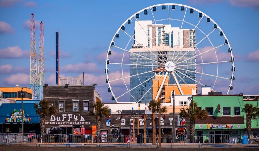 A ferris wheel stands in front of a building, symbolizing fun at Myrtle Beach Weekend Getaway.