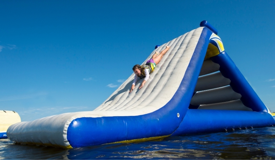 An individual sliding down a vibrant inflatable water slide at Shark Wake Park, a  best Myrtle Beach amusement parks.