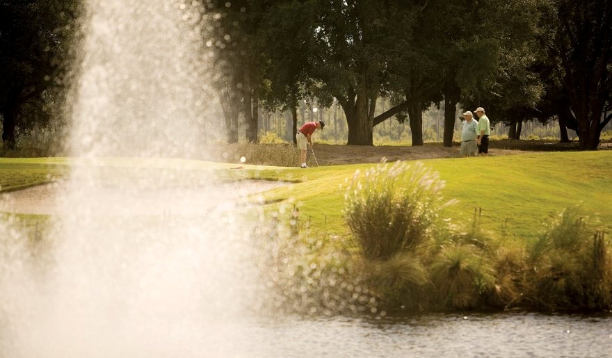 A group of people engage in golf near a fountain, highlighting the prime location and the benefits of  Myrtle Beach Group Golf Packages.