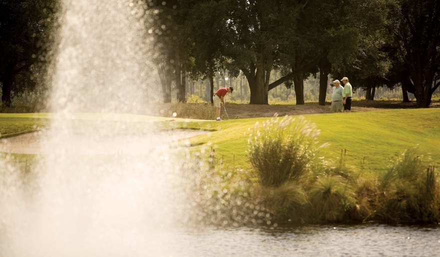 A group of people engage in golf near a fountain, highlighting the prime location and the benefits of  Myrtle Beach Group Golf Packages.