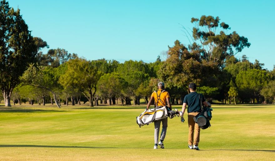 Two golfers walk across a lush golf course with conveying a serene, leisurely atmosphere highlighting the best times to visit Myrtle Beach golf course.