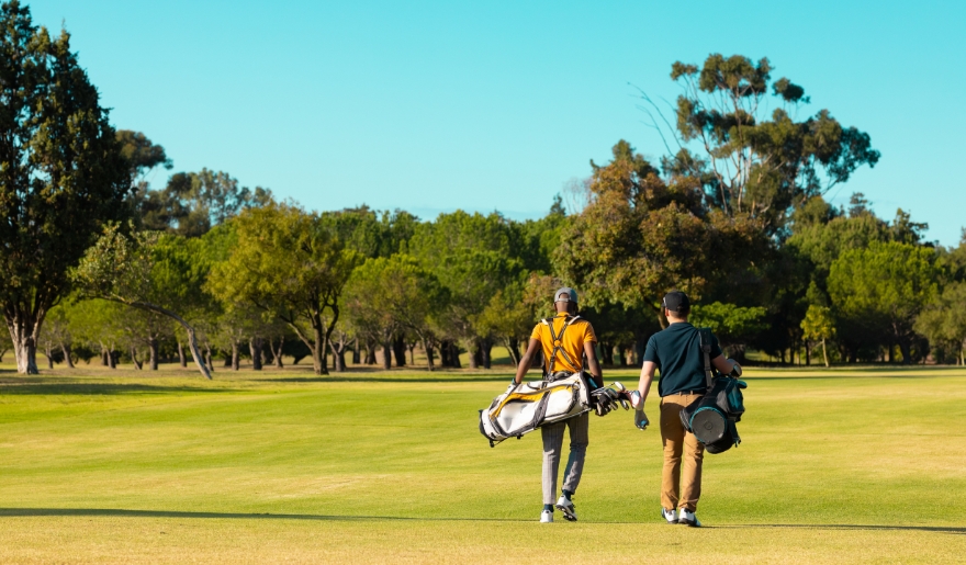 Two golfers walk across a lush golf course with conveying a serene, leisurely atmosphere highlighting the best times to visit Myrtle Beach golf course.