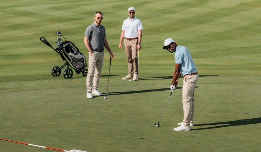 Three men playing golf on a green course at Myrtle Beach golf course.