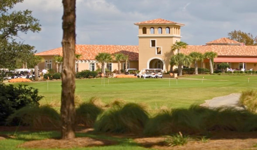 Expansive golf course with a prominent building in the background at Grande Dunes Golf part of Myrtle Beach Group Golf Packages.