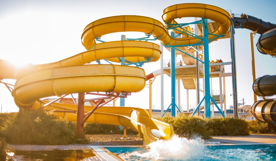 A vibrant yellow water slide descends into a pool at Myrtle Waves Water Park, showcasing a popular attraction in Myrtle Beach.