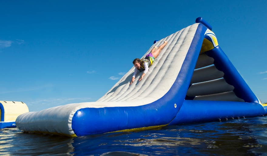 A person slides down an inflatable water slide at Shark Wake Park in Myrtle Beach Water Parks, enjoying a fun summer day.