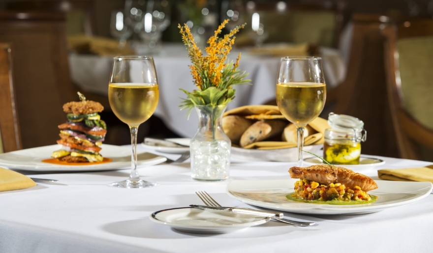 A table set with two plates of food and two glasses of wine at Waterscapes, Myrtle Beach Water Parks.