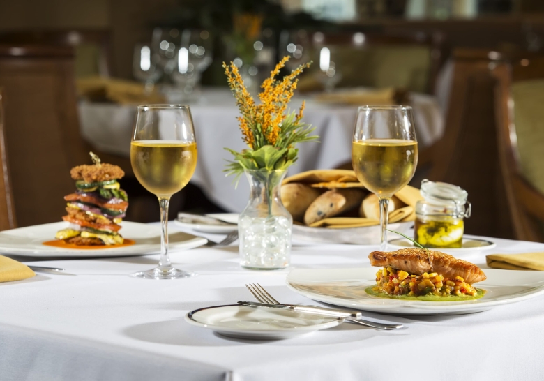 A table set with two plates of food and wine glasses, showcasing on-site dining at WaterScapes near Myrtle Beach Sports Center.