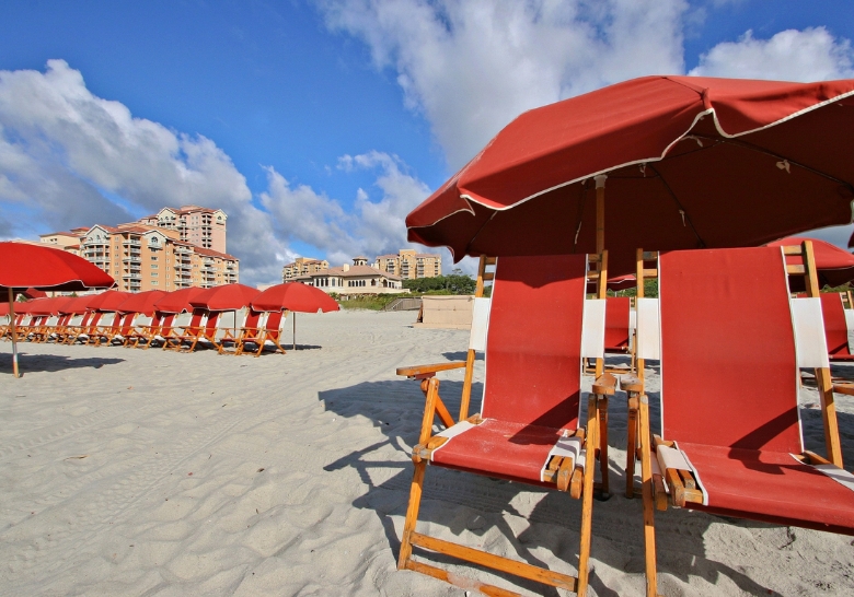 Beach chairs and colorful umbrellas set up on the sand, with a view of the ocean at Marina Inn.