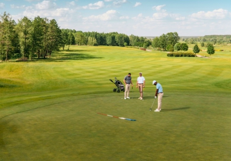 Three golfers enjoying a game on a lush green course near Myrtle Beach Hotel for Large Groups.
