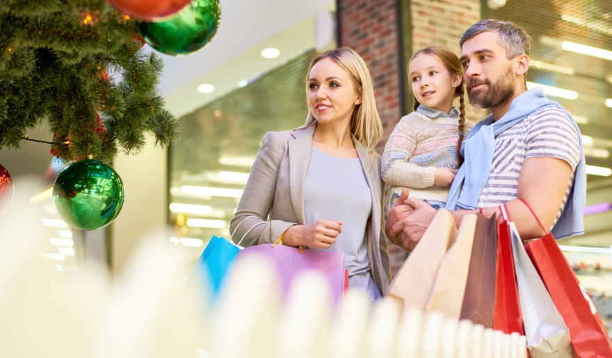 A family happily carries shopping bags while participating in holiday events at Barefoot Landing mall in Myrtle Beach.