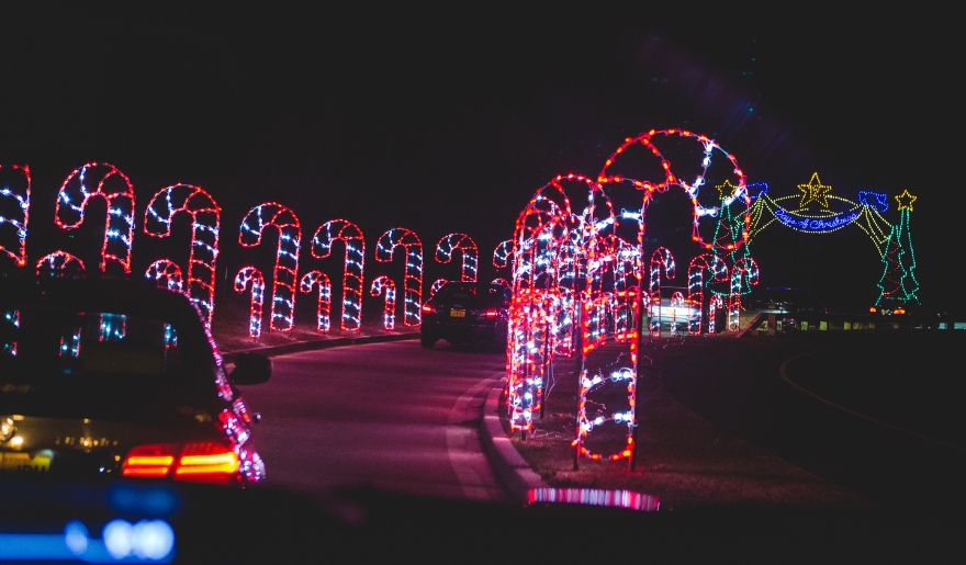 Bright Christmas lights decorate a road in Myrtle Beach, with cars traveling through the Conway Celebration of Lights scene.