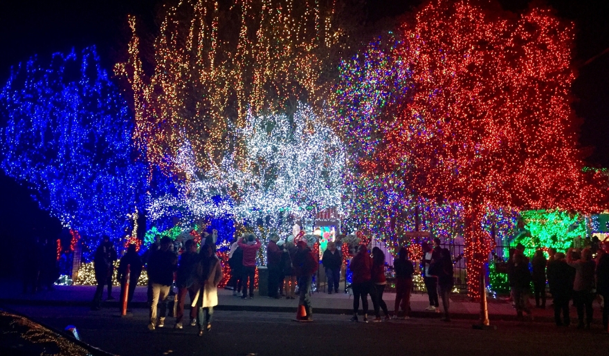 A group of people stands in front of a brightly lit house during the Myrtle Beach Christmas Winter Wonderland event.
