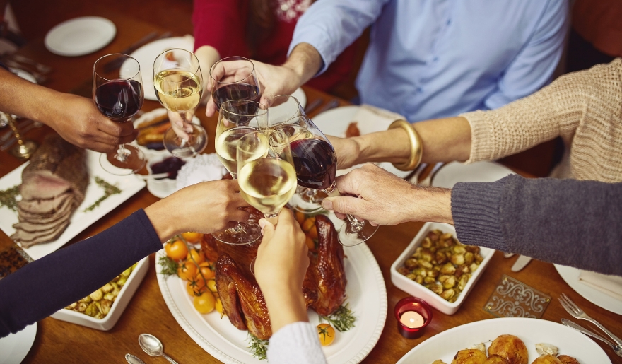 A group of people joyfully toasting with wine glasses at a dinner table during a New Year’s event at House of Blues.