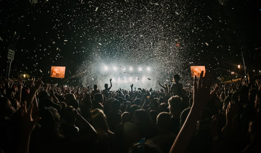 A lively crowd at a concert celebrating New Year's Eve, with colorful confetti falling at Myrtle Beach's Market Common.