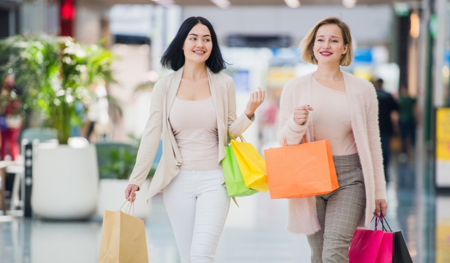 Two women walk through an airport in Myrtle Beach, carrying shopping bags from Tanger Outlets in January.