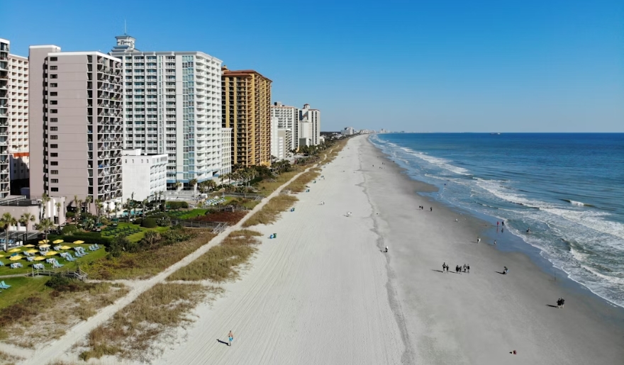 Myrtle Beach in January, featuring tall buildings alongside a sandy beach under a clear blue sky.