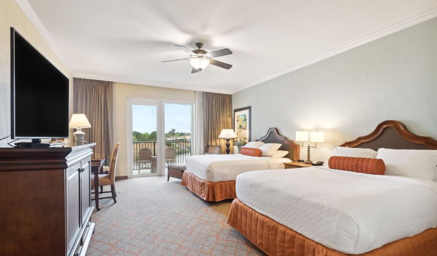 A cozy hotel room in Marina Inn at Grande Dunes with two beds, and a balcony, ideal for a vacation in Myrtle Beach in March.