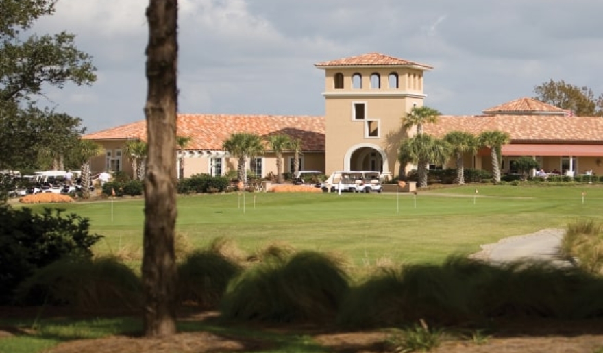 A scenic golf course featuring a large building and palm trees, highlighting Myrtle Beach travel tips for golfers.