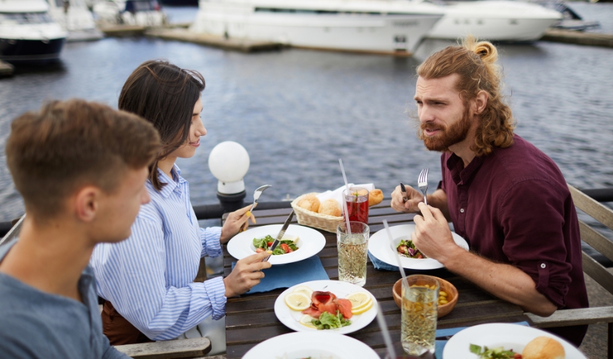 Three people enjoying a meal at a table, surrounded by various dishes, highlighting waterfront dining in Myrtle Beach.