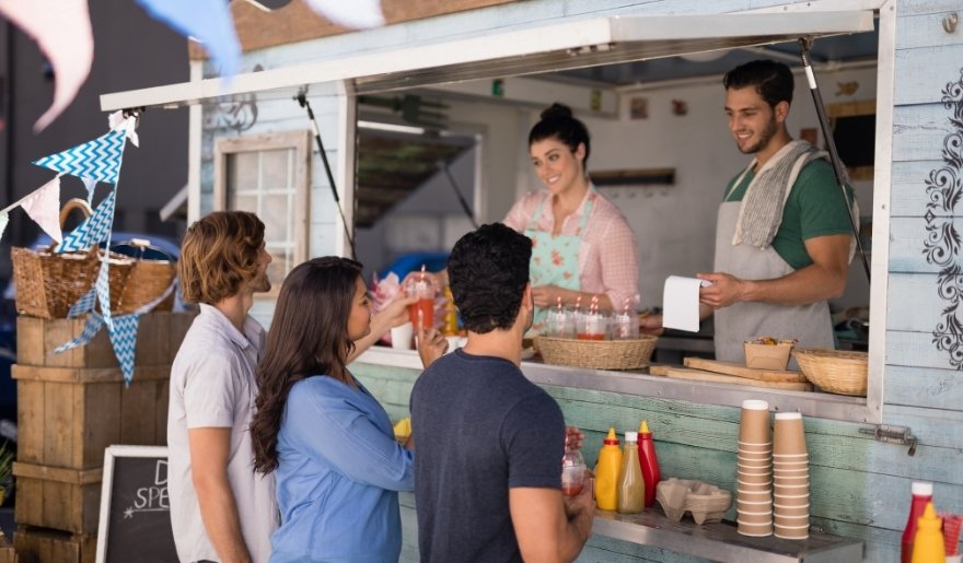 People socializing around a food stand during the Myrtle Beach Food Truck Festival in April, showcasing local cuisine.