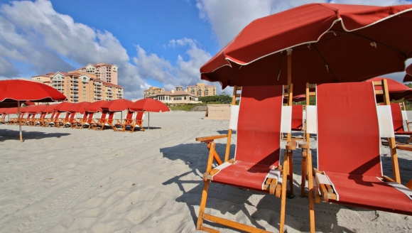 A row of beach chairs and umbrellas on the sand, showcasing the private beach access at ONEFlight Myrtle Beach Classic Hotel.