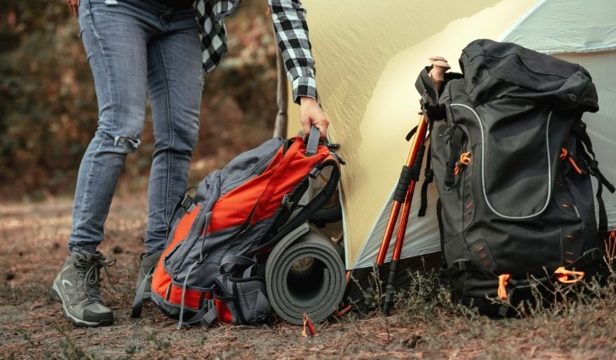 Hiker organizing essential gear with backpack, trekking poles, and tent setup at Myrtle Beach trails