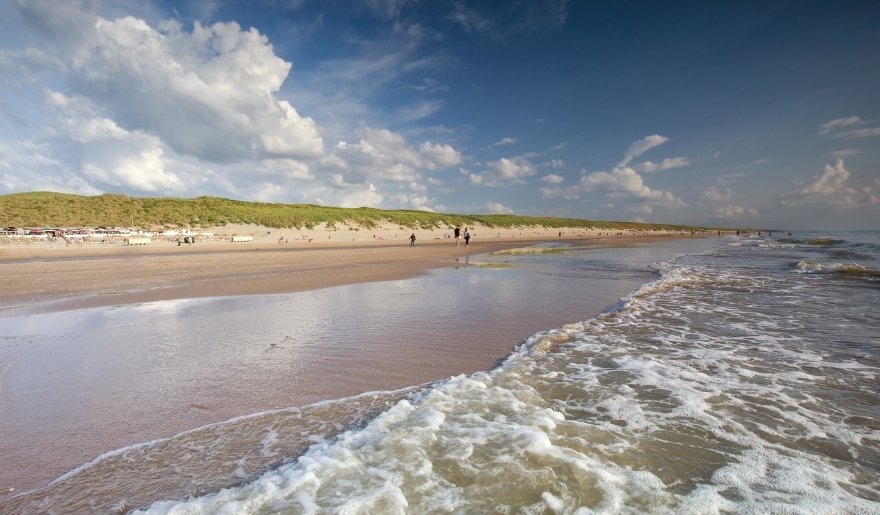 Ocean waves roll onto sandy shore at Huntington Beach State Park under a bright sky