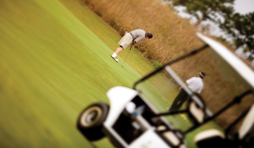 A golfer takes a shot on a vibrant green course, showcasing the ideal fall season for visiting Myrtle Beach.